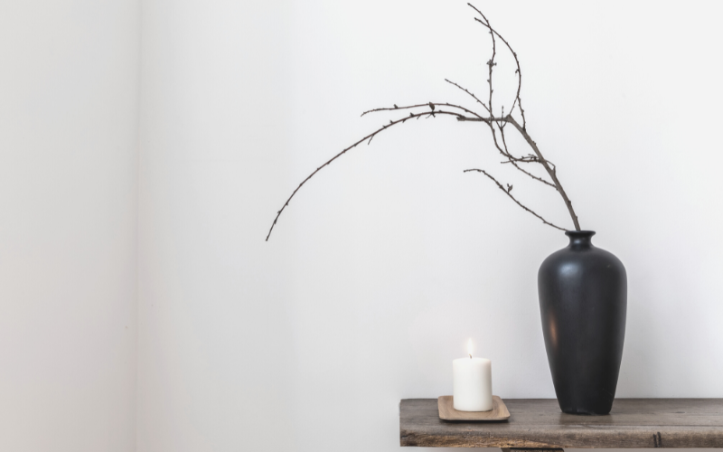 20 reasons to own less stuff. Photo shows a table with a vase and a candle